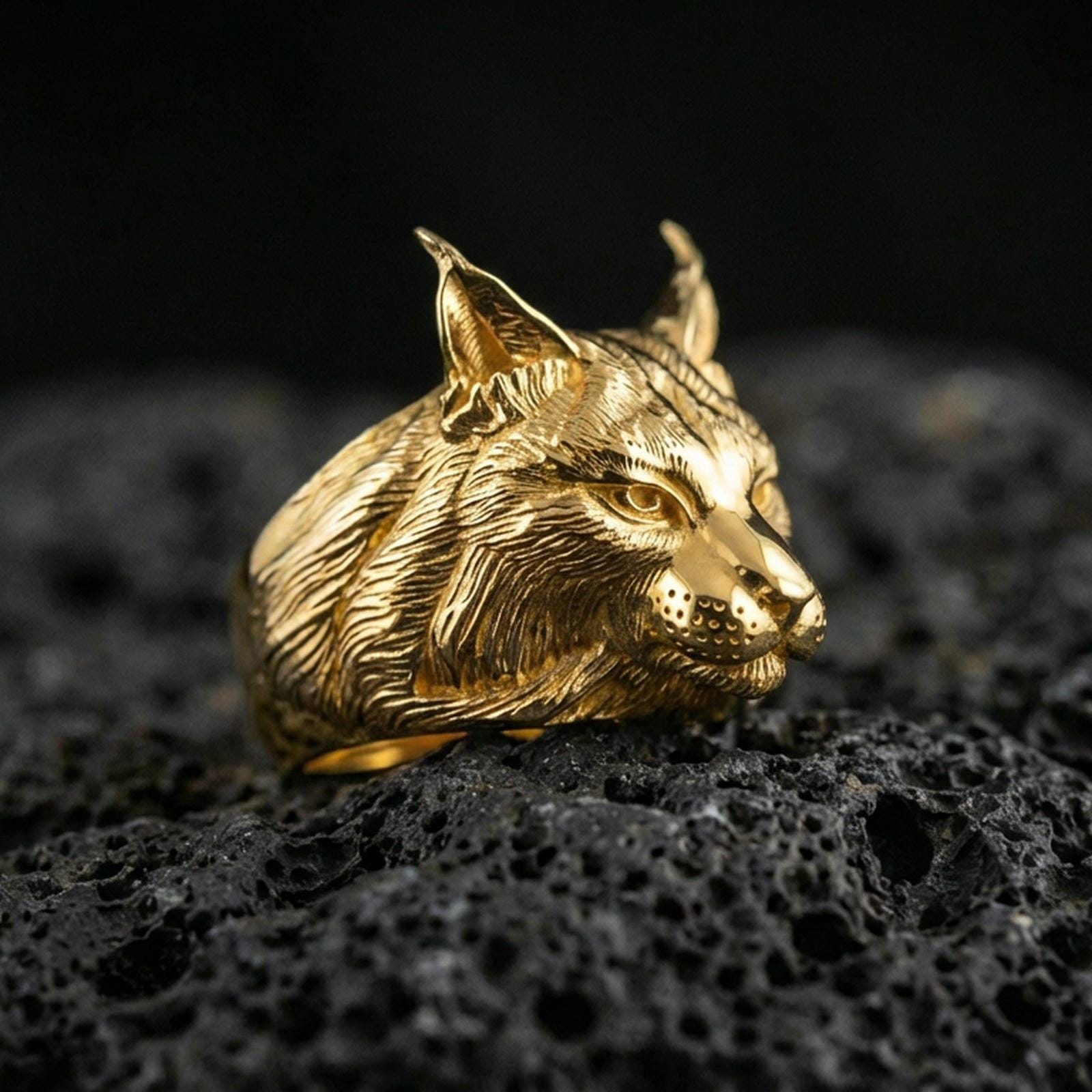 Gold plated lynx ring on porous volcanic stone, premium dark studio shot emphasizing the wild cat head relief and engraved fur texture