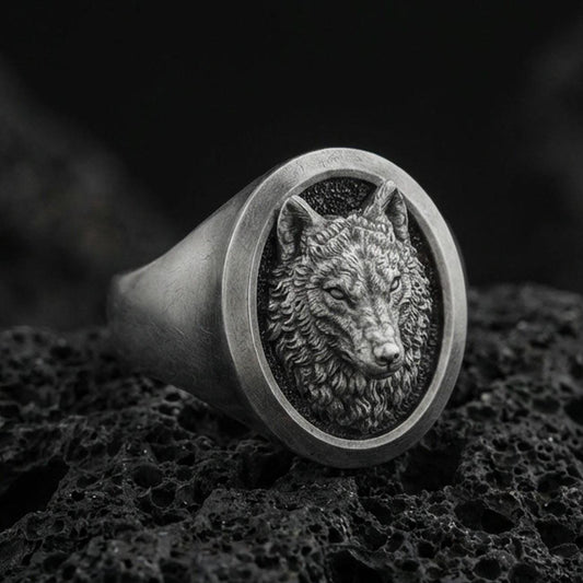 Oxidized sterling silver wolf signet ring on volcanic rock, macro closeup with dark textured backdrop