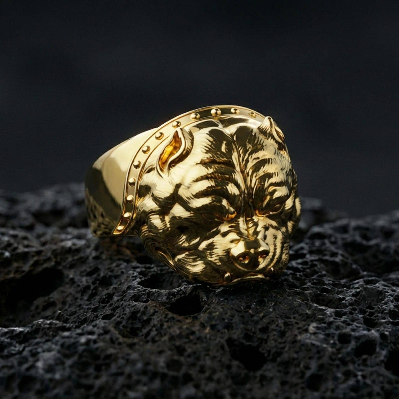 Gold plated bulldog head ring on porous volcanic stone, premium dark studio shot emphasizing the engraved fur lines and bold canine expression