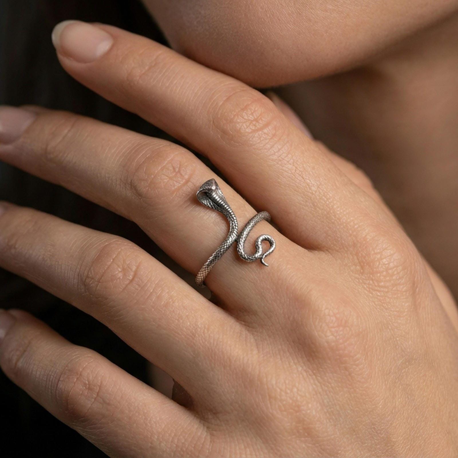 Oxidized cobra snake ring worn on finger, lifestyle close-up focusing on the raised hood, coiled body, and detailed scale texture