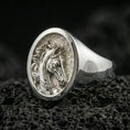 Load image into Gallery viewer, Polished silver horse head signet ring on volcanic rock surface, close-up highlighting the round bezel, carved mane detail, and smooth tapered band
