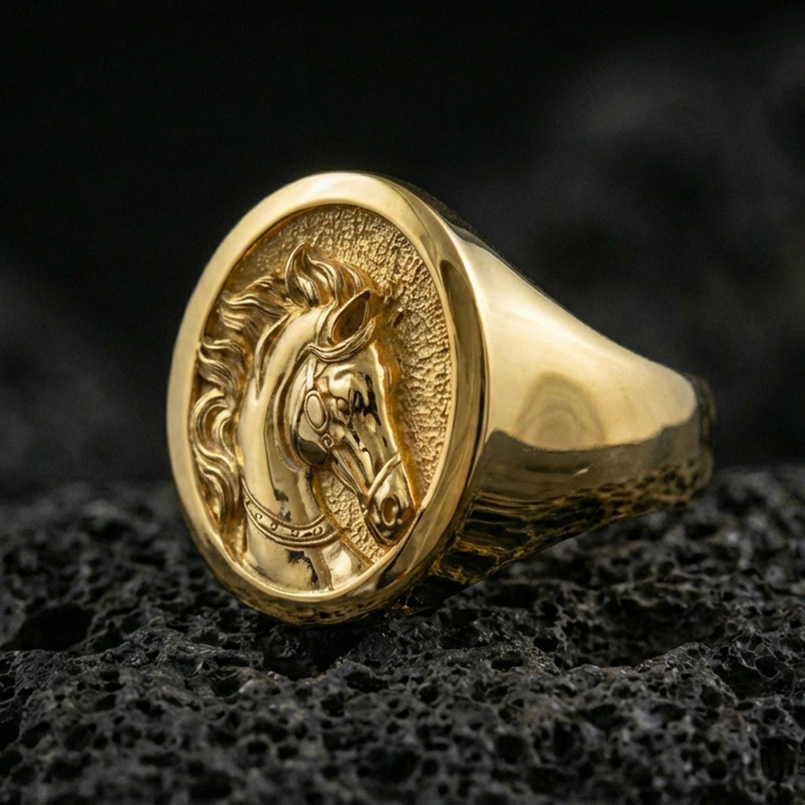Gold plated horse signet ring on porous volcanic stone, premium dark studio shot emphasizing the equestrian profile relief and bold round signet top