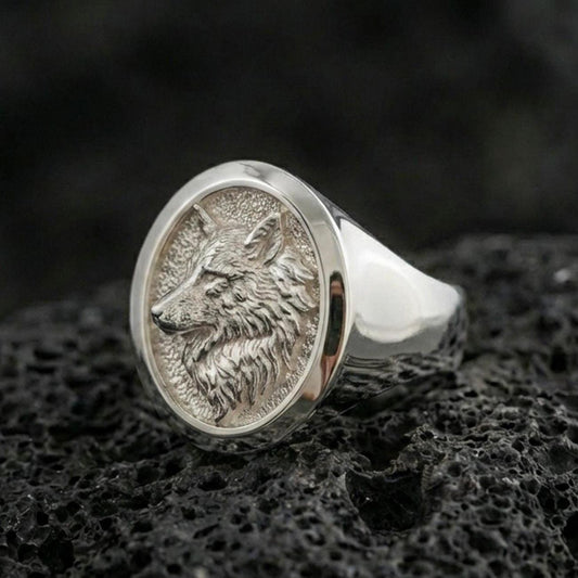 Polished silver wolf head ring on volcanic stone, clean profile carving and premium studio lighting
