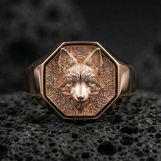 Rose gold plated fox head signet ring on rugged volcanic rock surface, high-end studio macro composition