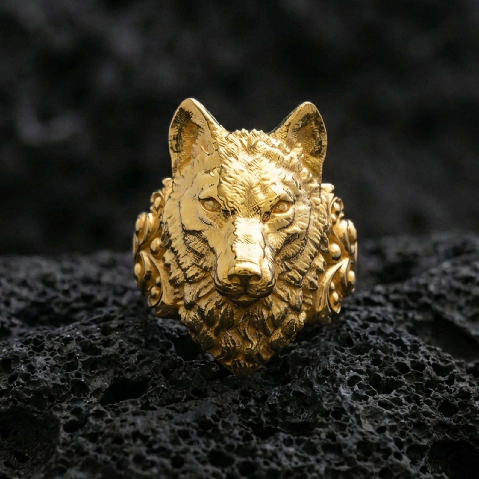 Detailed gold plated wolf head ring photographed on black volcanic stone with sharp focus and dramatic shadows