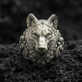 Load image into Gallery viewer, Close-up of an oxidized sterling silver wolf head ring centered on porous volcanic rock in a dark studio setting
