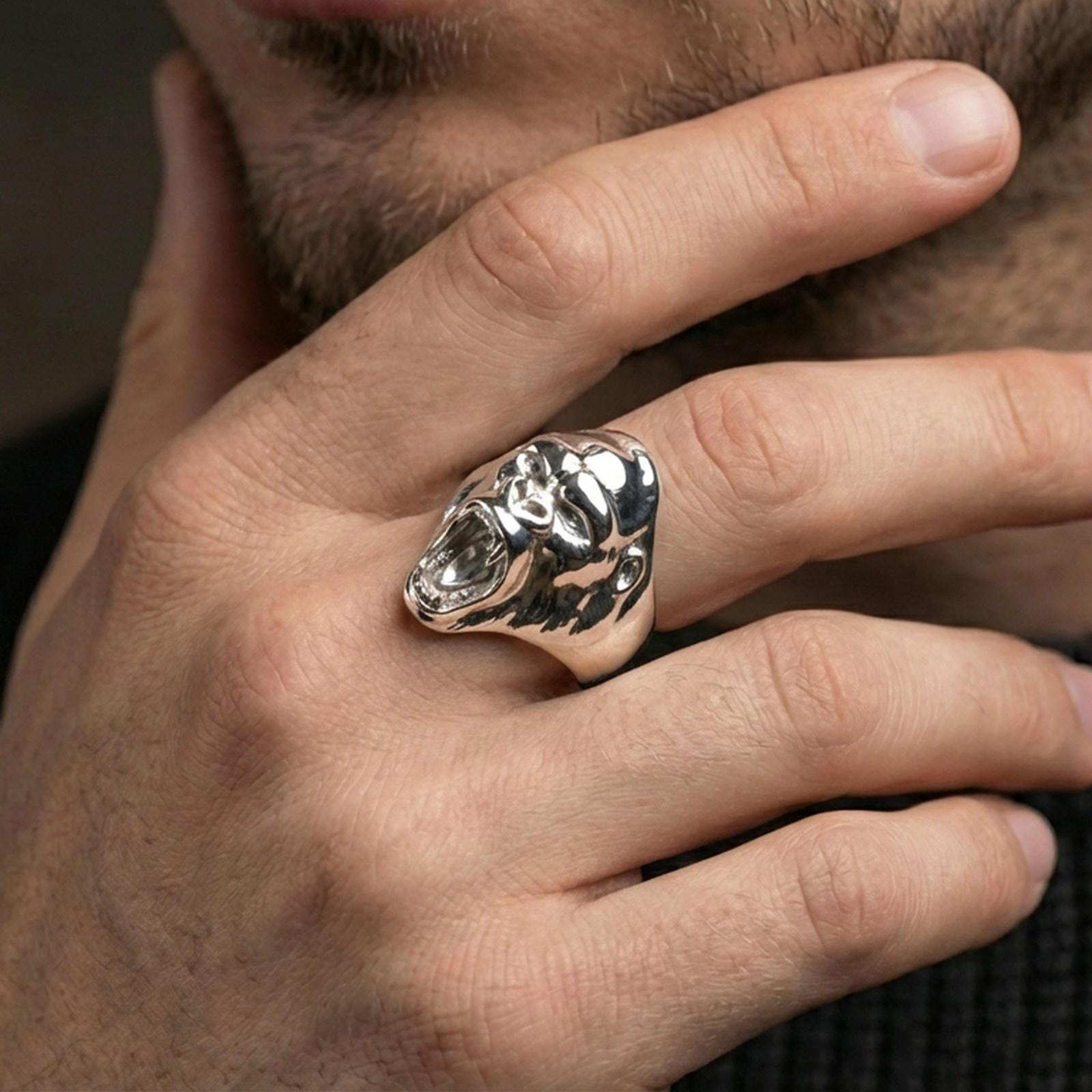 Polished silver gorilla head ring on a hand, close-up emphasizing the open mouth and carved fur texture