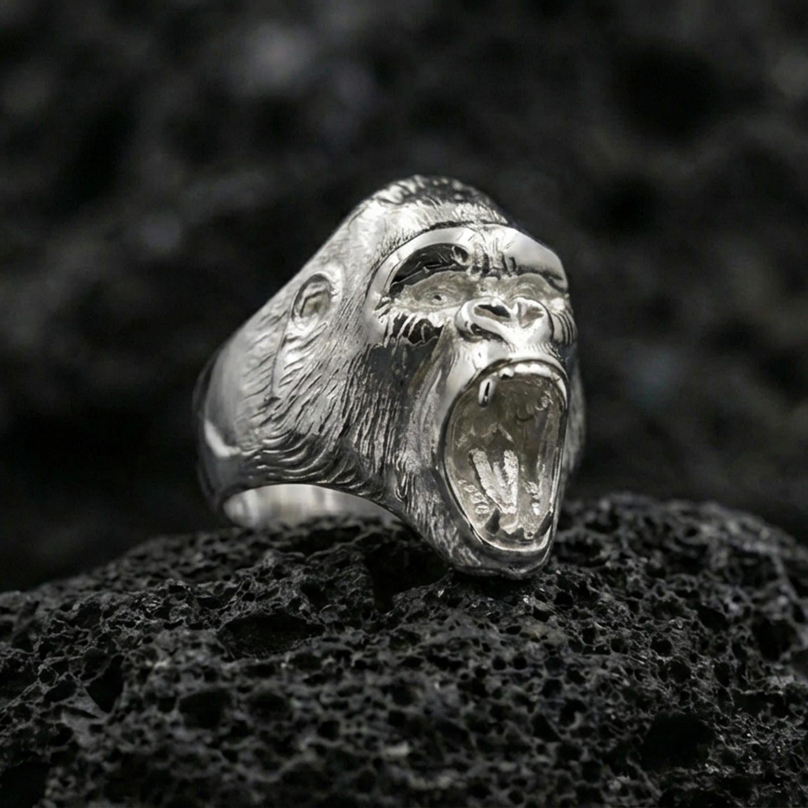 Polished silver gorilla ring photographed on textured volcanic rock with sharp focus and premium lighting