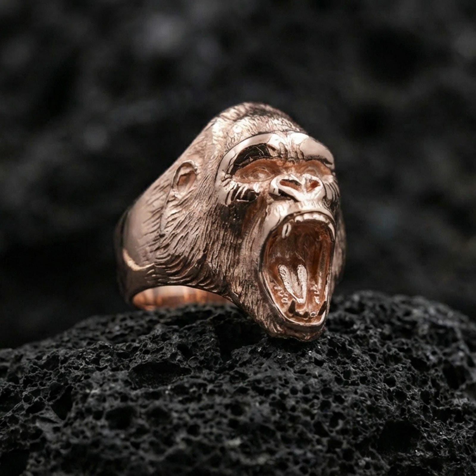 Rose gold plated gorilla ring displayed on rugged volcanic rock with dramatic shadows and high detail
