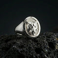 Load image into Gallery viewer, Polished silver leopard head signet ring on volcanic rock surface, close-up highlighting the round bezel edge, feline facial contours, and smooth tapered band
