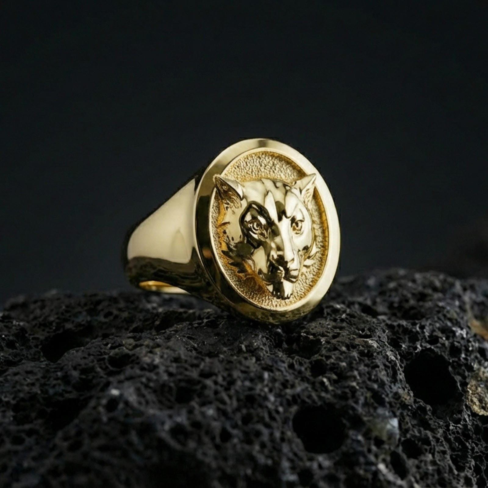 Gold plated leopard signet ring on porous volcanic stone, premium dark studio shot emphasizing the bold big cat relief and classic round signet silhouette