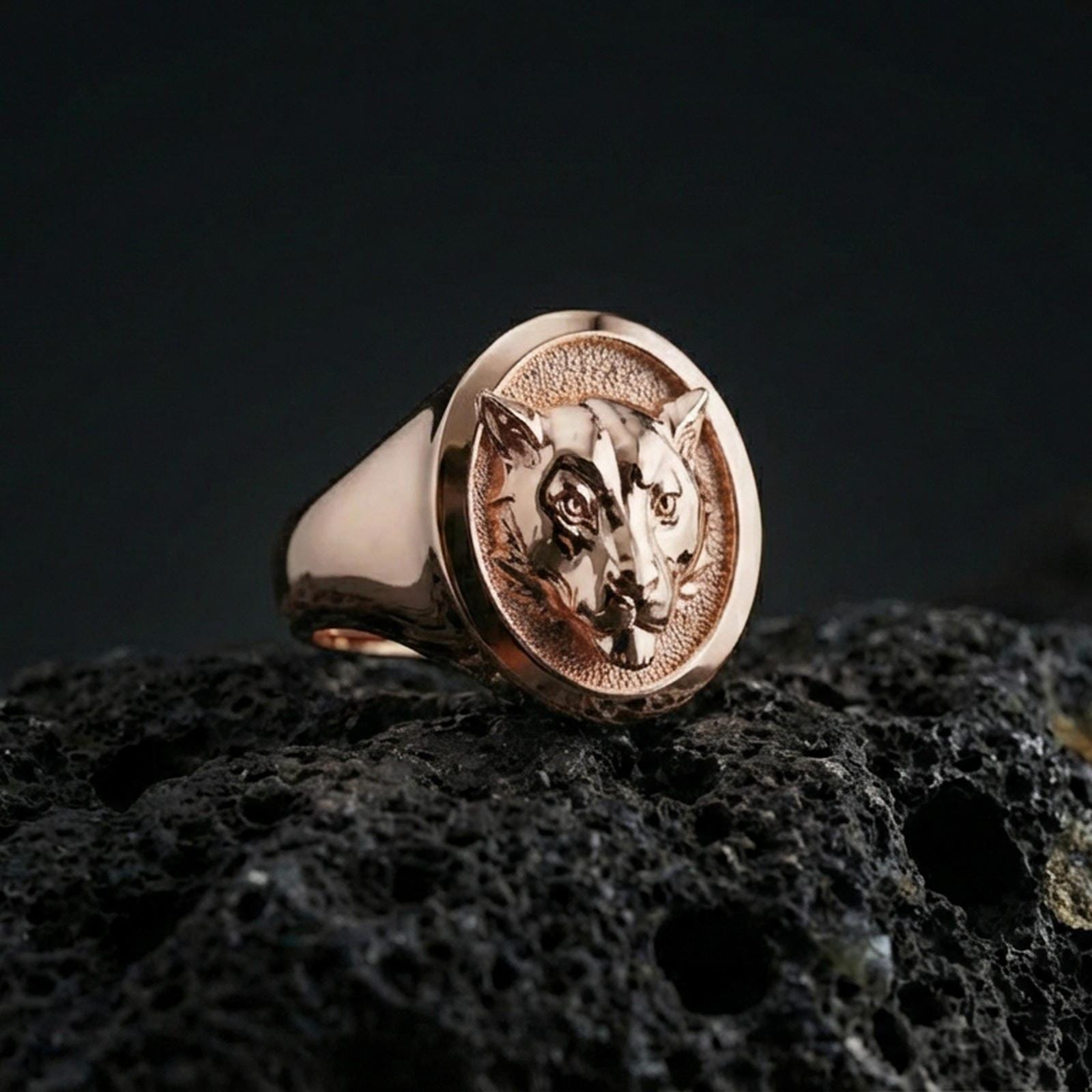 Rose gold plated leopard head ring on volcanic rock, sharp macro product photo showcasing the detailed feline portrait and round signet top