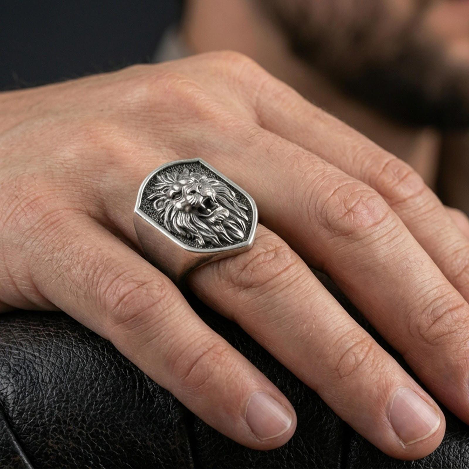 Oxidized sterling silver roaring lion ring worn on a finger, showing the bold signet face and strong profile