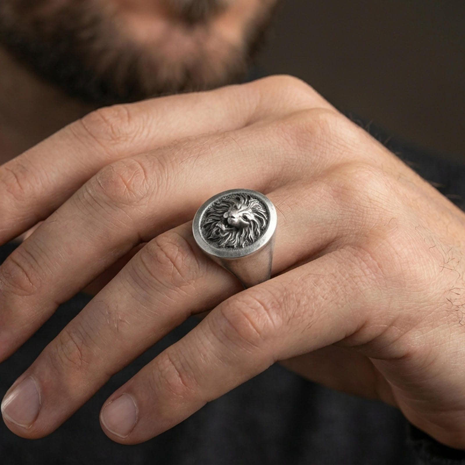 Oxidized lion signet ring worn on finger, lifestyle close-up emphasizing the bold roaring lion head and vintage-inspired depth