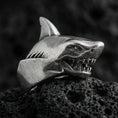 Load image into Gallery viewer, Close-up of an oxidized sterling silver shark head ring on porous volcanic rock in a dark studio setting
