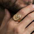 Load image into Gallery viewer, Gold plated royal lion signet ring worn on finger, lifestyle wear shot focusing on the crowned lion symbol and bold statement look
