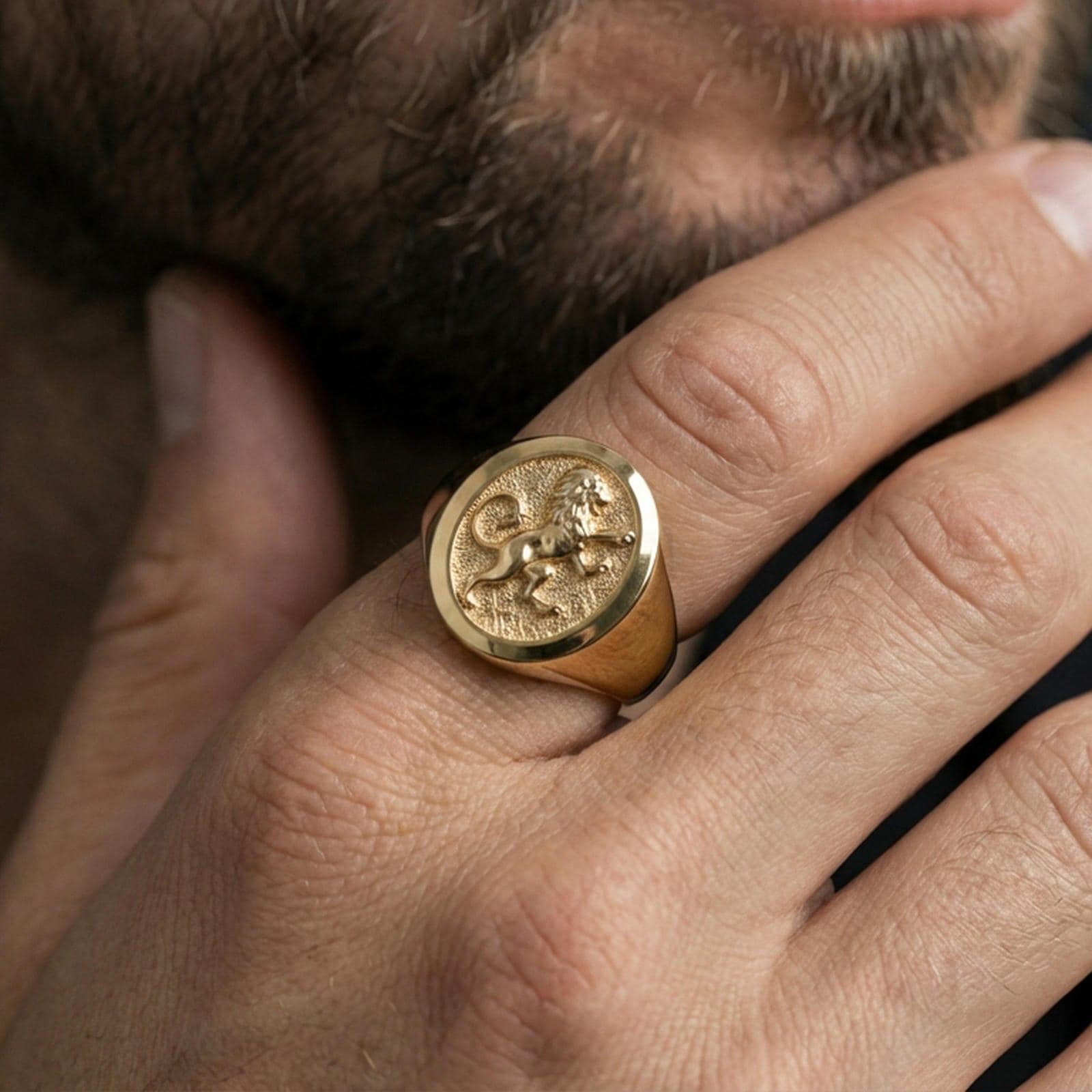 Gold plated royal lion signet ring worn on finger, lifestyle wear shot focusing on the crowned lion symbol and bold statement look