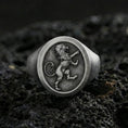 Load image into Gallery viewer, Oxidized sterling silver heraldic lion signet ring on black volcanic rock, macro close-up highlighting the crowned lion emblem and dark recessed background

