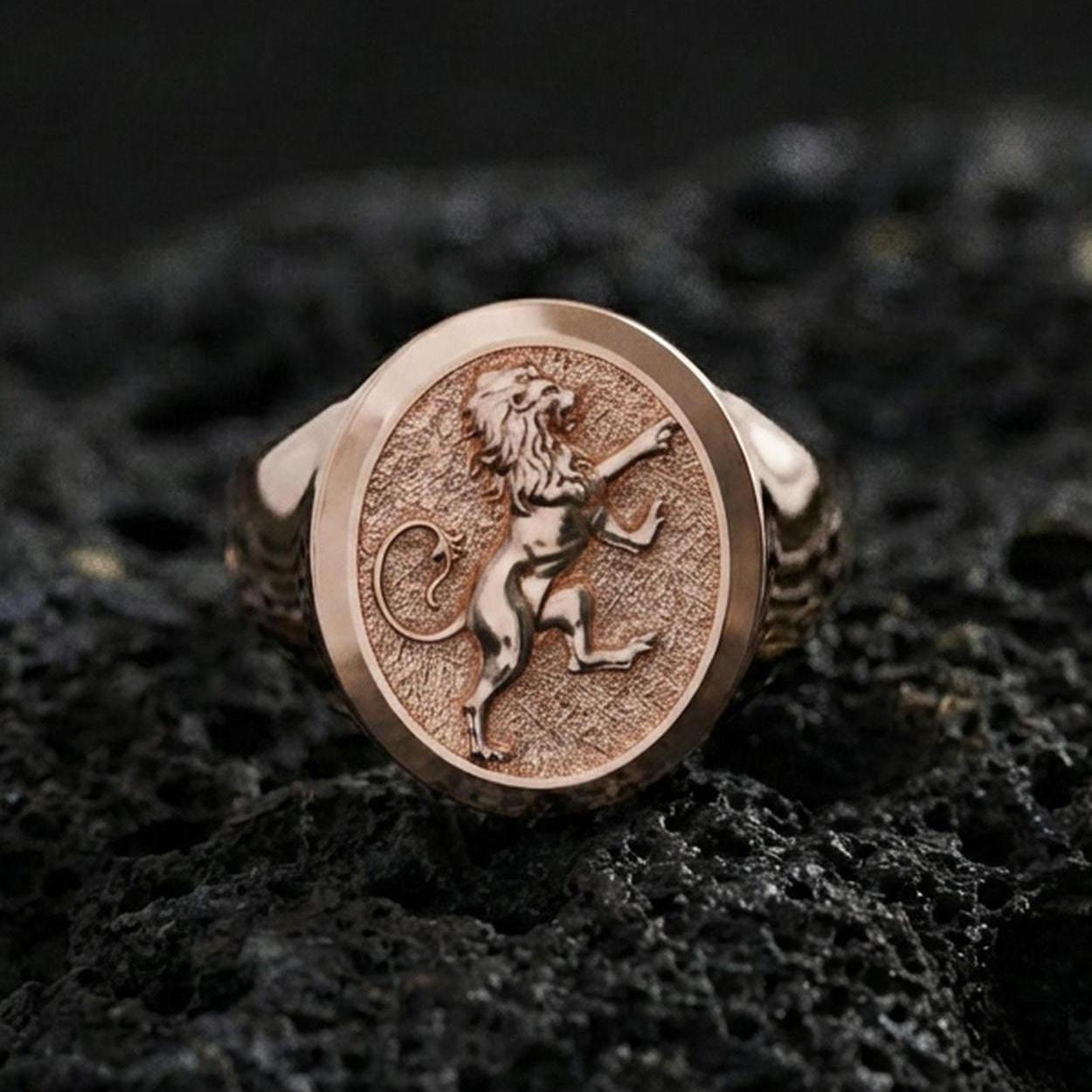 Rose gold plated royal lion signet ring on textured volcanic rock, luxury macro photo showcasing the lion crest relief and refined bezel finish