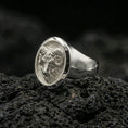 Load image into Gallery viewer, Polished silver ram head ring on textured volcanic stone, macro focus on the curved horns and face detail
