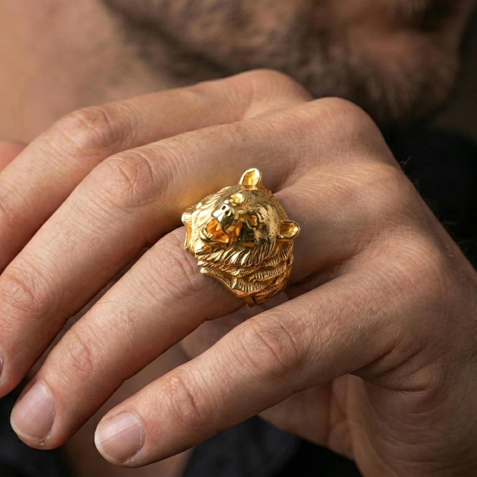 Gold plated bear ring worn on a finger against a dark minimal background, strong statement jewelry styling