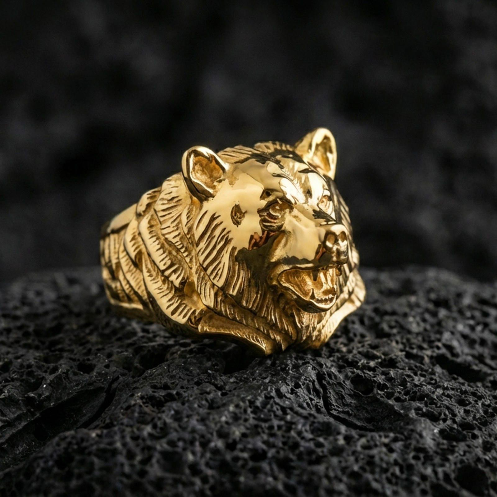 Gold plated bear head ring on black volcanic rock, close-up emphasizing the sculpted muzzle and dimensional texture