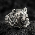 Load image into Gallery viewer, Close-up of an oxidized sterling silver bear head ring on porous volcanic rock with dark premium studio lighting
