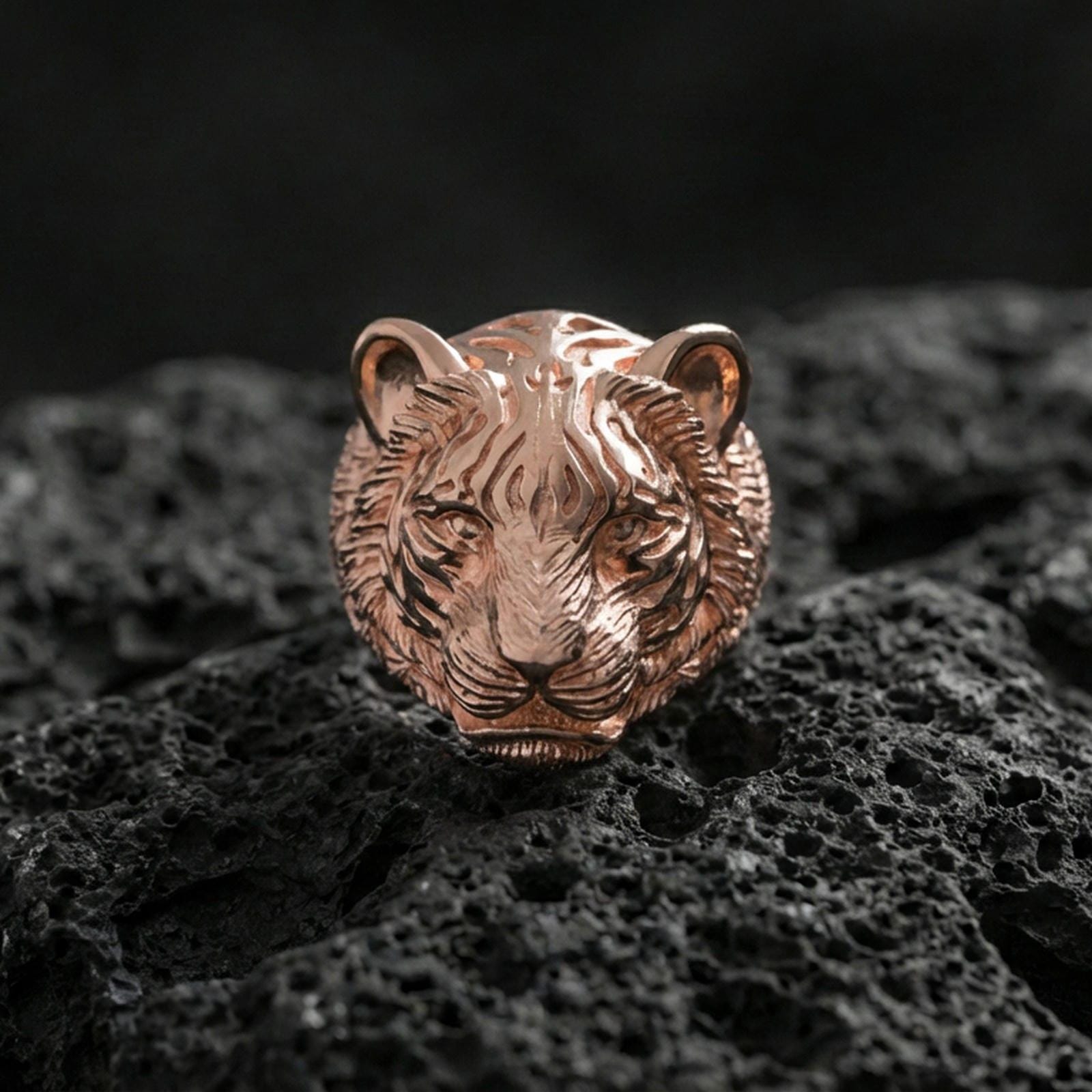 Rose gold plated tiger face ring on porous volcanic rock with controlled highlights and deep contrast
