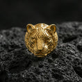 Load image into Gallery viewer, Gold plated tiger head ring on black volcanic rock, close-up emphasizing the sculpted eyes and fur texture
