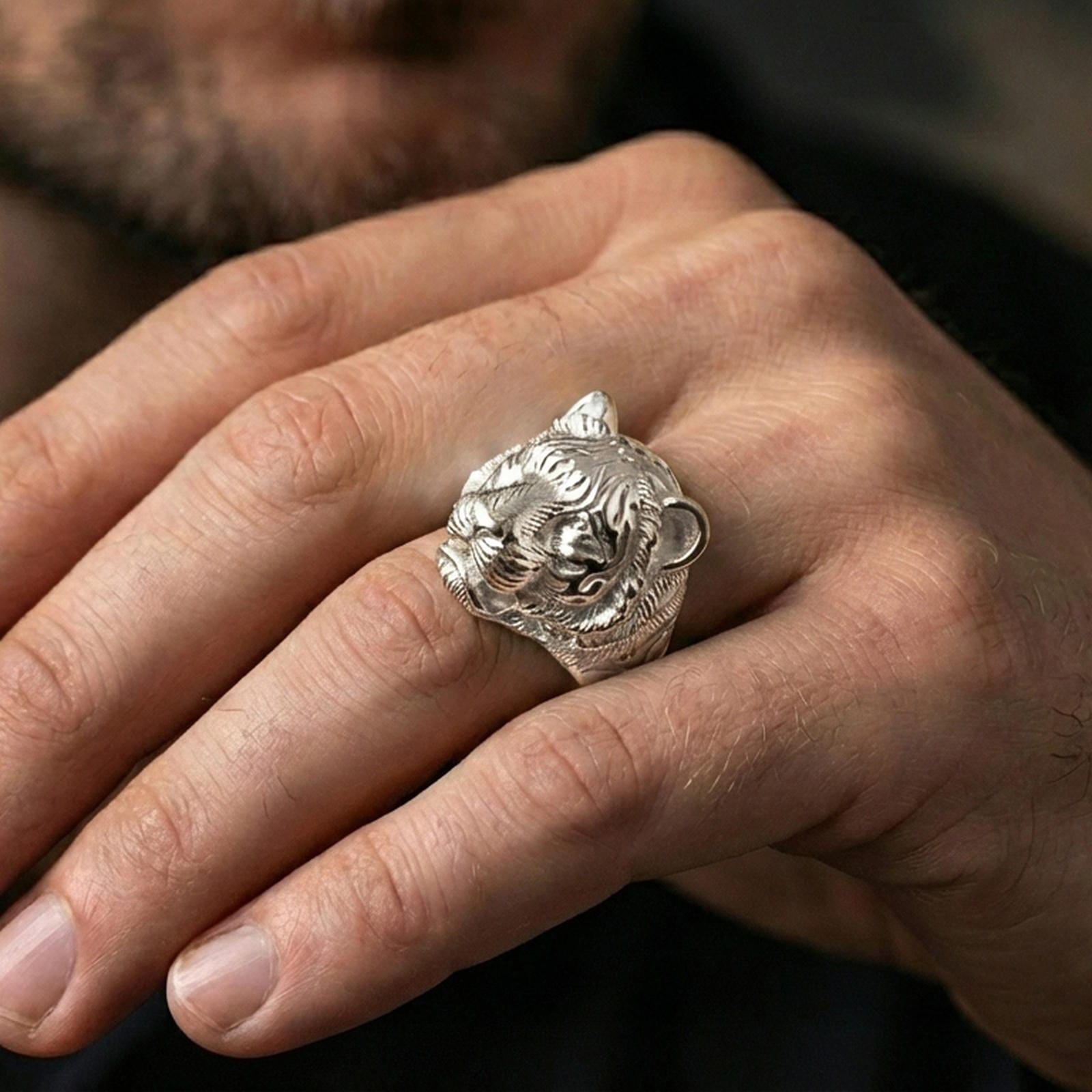 Polished silver tiger head ring on a hand, close-up highlighting the engraved stripes and relief depth