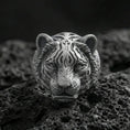 Load image into Gallery viewer, Close-up of an oxidized sterling silver tiger head ring on porous volcanic rock with dramatic studio shadows
