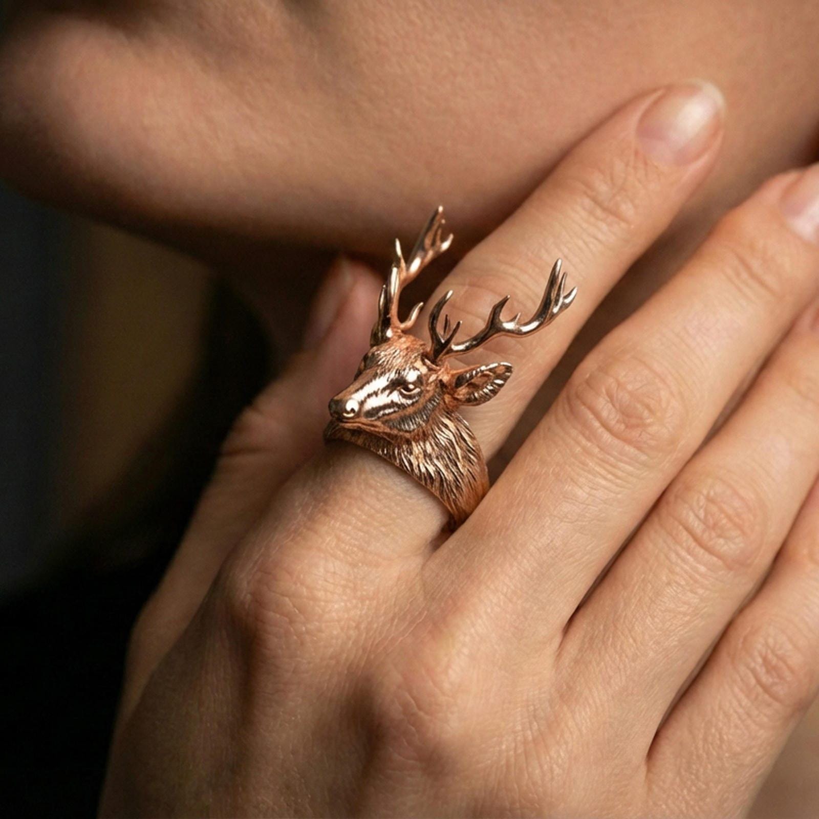 Rose gold plated stag head ring worn on a finger, macro view focusing on the face and antler craftsmanship