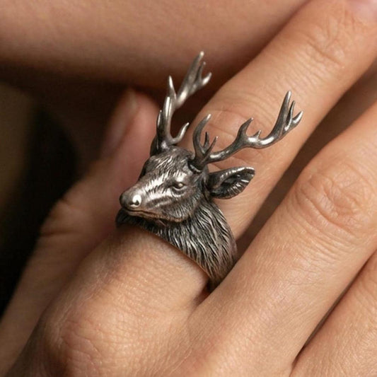 Oxidized sterling silver stag ring worn on a finger, angled view showing the raised antlers and profile