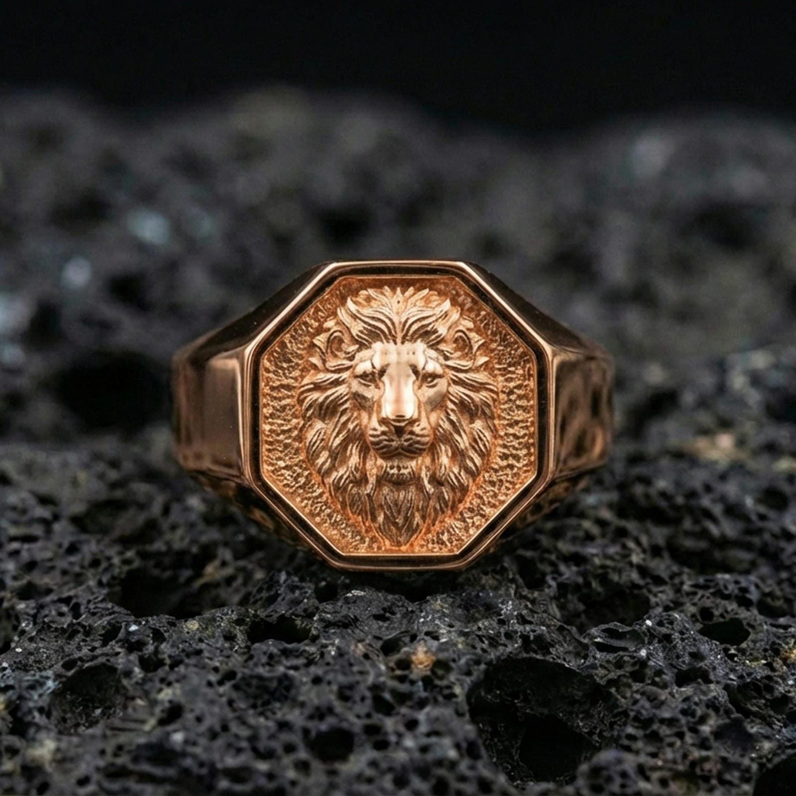 Rose gold plated lion head signet ring on porous volcanic rock, premium studio lighting and shallow depth