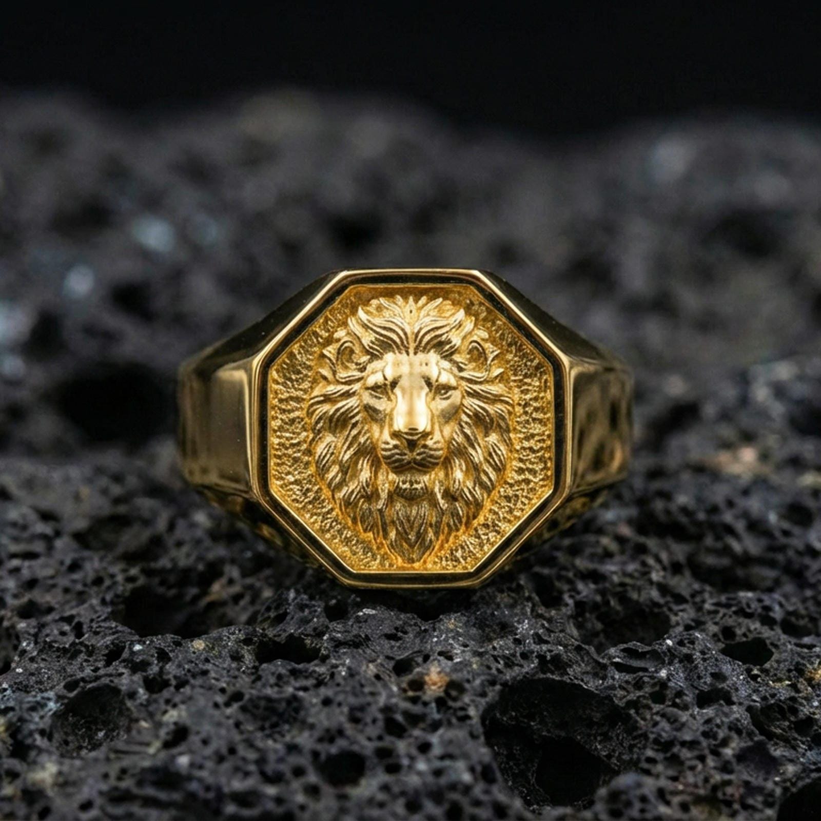 Gold plated octagon lion signet ring on black volcanic rock with crisp highlights and deep shadows