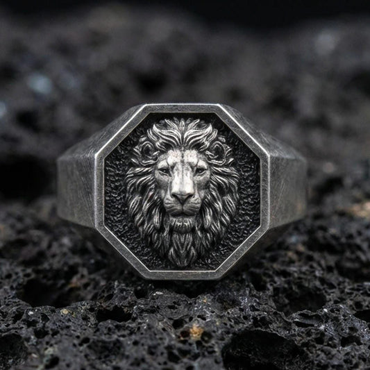 Close-up of an oxidized sterling silver octagon lion signet ring on porous volcanic rock in a dark studio