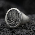 Load image into Gallery viewer, Close-up of an oxidized sterling silver forest engraved signet ring on porous volcanic rock in a dark studio
