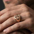 Load image into Gallery viewer, Sterling silver compass rose ring on a finger, macro lifestyle shot featuring the rose gold plated finish and maritime navigation inspired signet design

