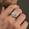 Load image into Gallery viewer, Sterling silver compass signet ring on a finger, macro lifestyle image emphasizing the polished silver finish and round compass rose face
