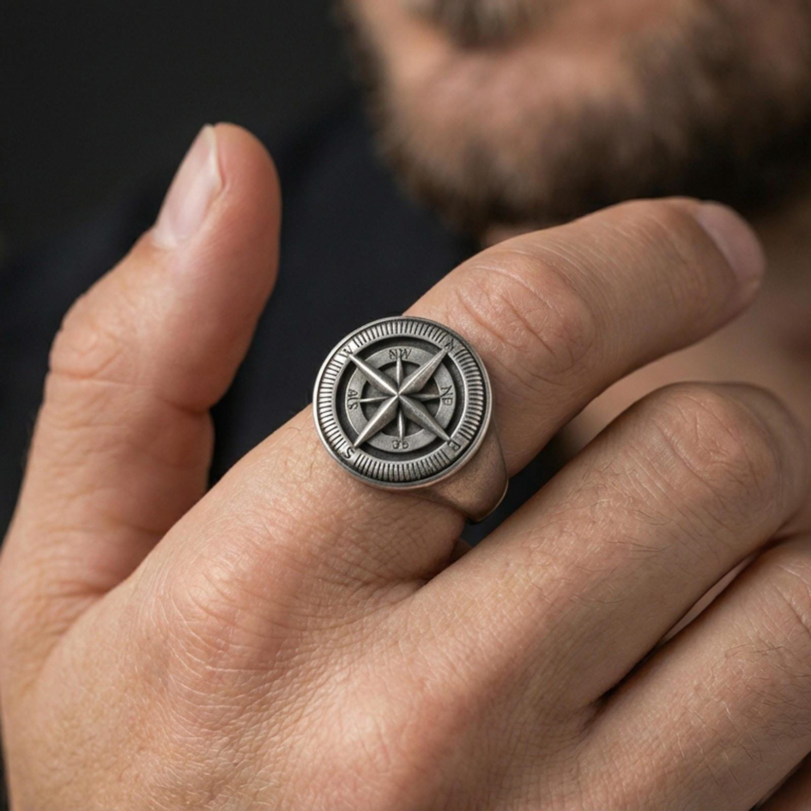 Sterling silver compass rose signet ring worn on a finger, close-up lifestyle shot highlighting the oxidized nautical compass design and engraved directional details