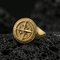 Load image into Gallery viewer, Sterling silver compass rose signet ring with a gold plated finish, maritime navigation symbol ring with engraved north south east west letters, macro on volcanic rock
