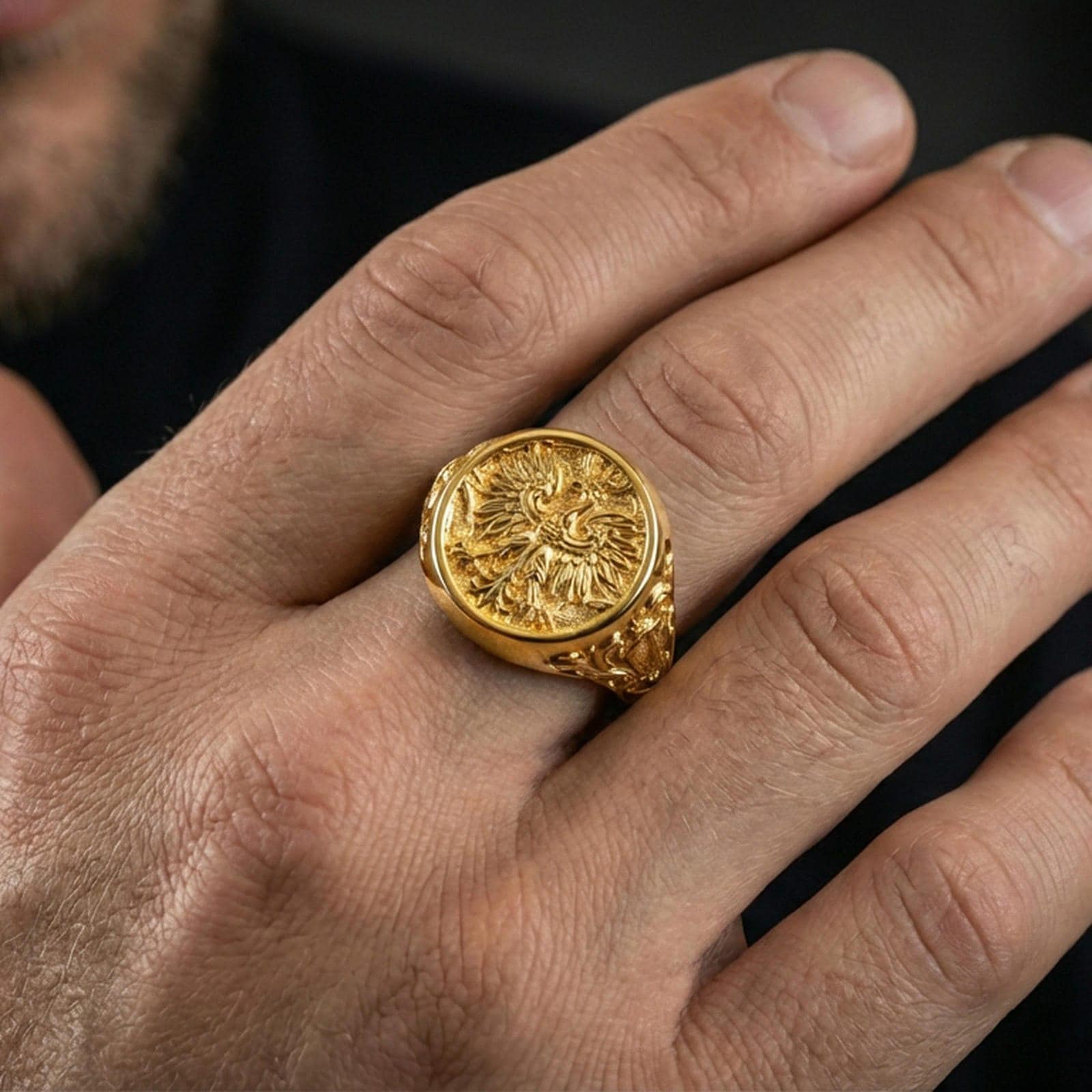 Sterling silver phoenix crest ring worn on a finger, close-up lifestyle photo showcasing the gold plated finish and bold round signet design