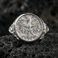 Load image into Gallery viewer, Sterling silver phoenix crest ring in a polished silver finish, ornate round signet design with layered feather engraving, close-up on volcanic stone
