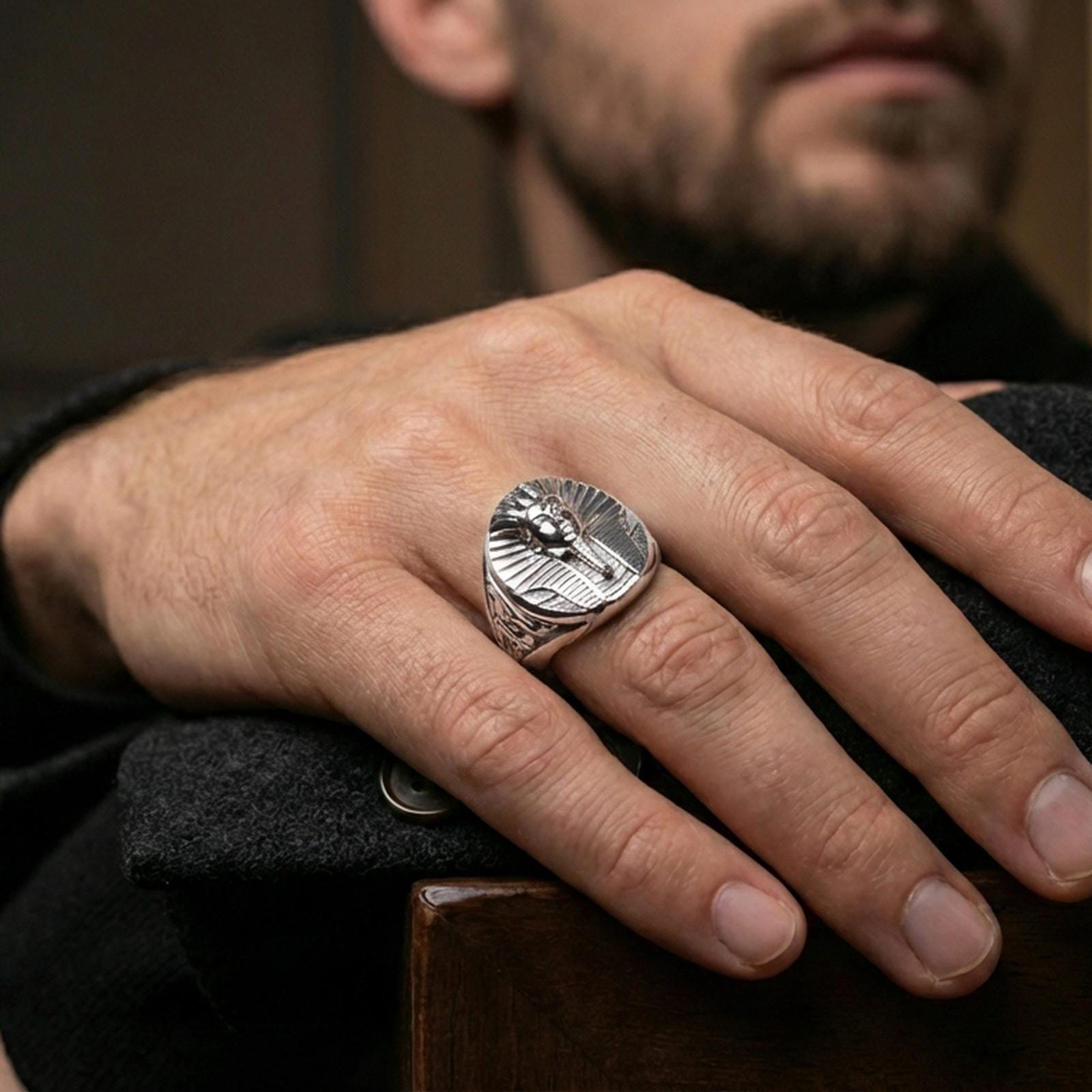 Sterling silver ancient Egypt statement ring on a finger, macro lifestyle image emphasizing the polished silver pharaoh relief and carved side details