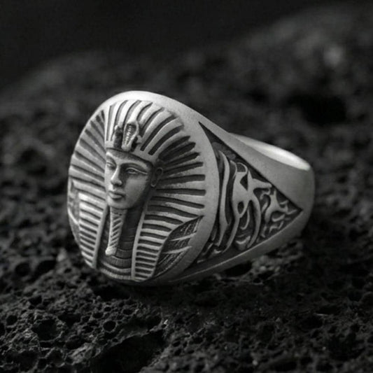 Sterling silver Egyptian pharaoh signet ring with an oxidized finish, oval face featuring a detailed royal pharaoh portrait and engraved side motifs, macro on black volcanic rock