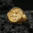 Load image into Gallery viewer, Sterling silver ancient Greek warrior signet ring with a gold plated finish, round face showing a helmeted soldier with spear and shield in high-relief detail, macro product shot on volcanic rock
