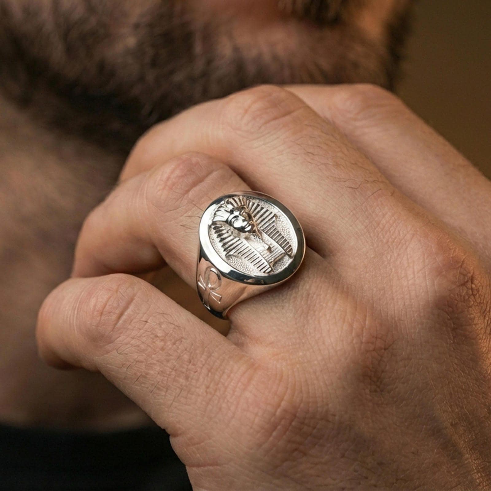 Sterling silver ancient Egypt statement ring on a finger, macro lifestyle image emphasizing the polished silver pharaoh portrait and detailed headdress engraving