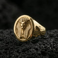 Load image into Gallery viewer, Sterling silver ancient Egypt signet ring with a gold plated finish, oval face showing a pharaoh portrait with geometric headdress lines and side ankh motif, macro product shot on volcanic rock
