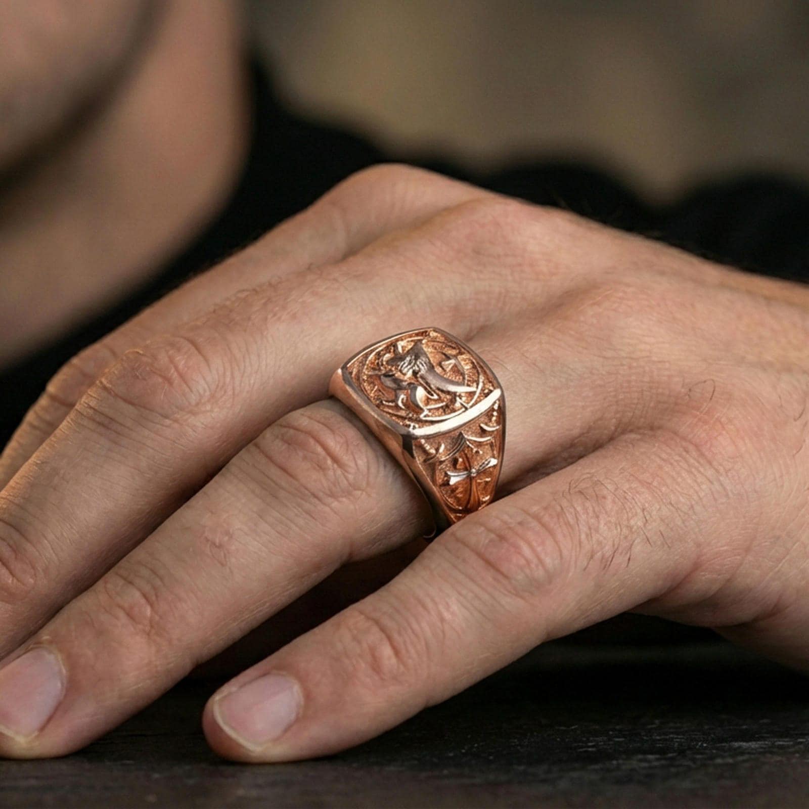 Sterling silver medieval lion signet ring on a finger, macro lifestyle shot featuring the rose gold plated finish and bold heraldic square face design