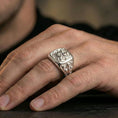 Load image into Gallery viewer, Sterling silver heraldic lion statement ring on a finger, macro lifestyle image emphasizing the polished silver finish and engraved crusader-style side details
